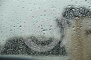 Raindrop on windshield and other car with blurred background