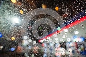 Raindrops adhere to the glass of the car in the rain at night on an electrically illuminated street at the petrol station