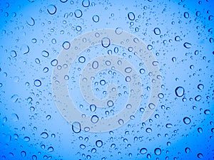 Raindrops on a blue glass, abstract blue background