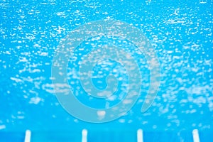 Raindrops in the blue swimming pool, gently ripple surface of water, blurred terrace foreground. Exterior tropical pool. Selective