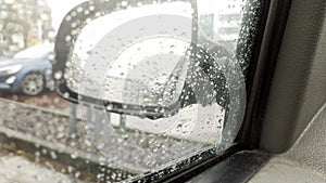 Raindrops on car window with blurry background of city streets background on rainy day in winter