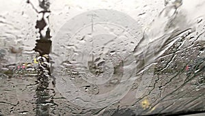 Raindrops on car window with blurry background of city streets background on rainy day in winter