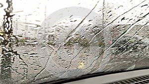 Raindrops on car window with blurry background of city streets background on rainy day in winter