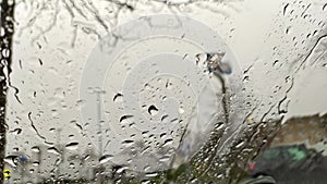 Raindrops on car window with blurry background of city streets background on rainy day in winter