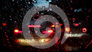 Raindrops on the car windshield with blurry traffic scene in the evening