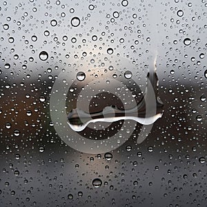 Raindrops cover a glass window creating a textured pattern across the surface