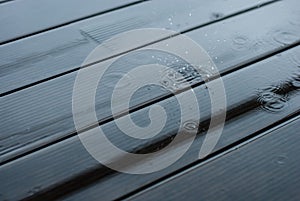 Raindrops fall on a wooden terrace