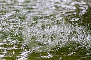 Raindrops falling to the floor in heavy rain day into a puddle on an splashy country road in spring offer refreshing water shower