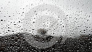 Raindrops on glass on the background of the escalator. The tractor digs the ground in the rain. Thunderstorm outside the window