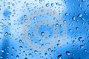 Raindrops on glass. Bright beautiful background of trendy blue color. Delicate classic backdrop. Water drop texture.