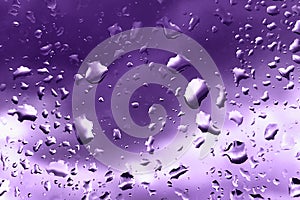 Raindrops on glass for purple backdrop rainy fall autumn weather. Abstract backgrounds with rain drops on window