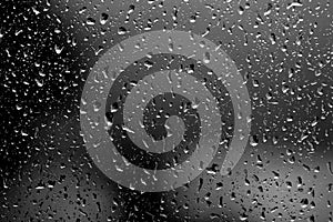 Raindrops on glass in rainy weather. Natural background black and white