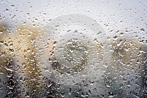 Raindrops on glass, window background view of buildings out of focus