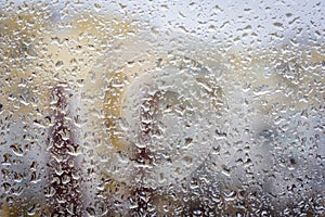 Raindrops on glass, window background view of buildings out of focus