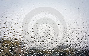 Raindrops on glass, window background view of buildings out of focus