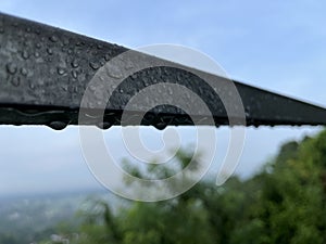 Raindrops on a metal fence after heavy rain