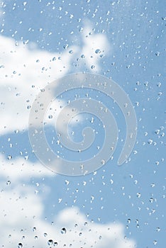 raindrops od window glass with blue sky and white cloud as background