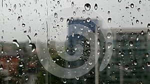 Raindrops pelting hard and fast onto a glass window pane