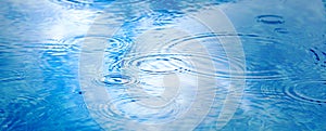 Raindrops on pool blue water surface. blue water texture as background. Stains circles on the water from rain. Long web baner