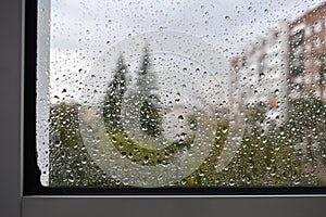 Raindrops on a rainy day on the window pane. Autumn cloudy weather through glass covered with rain drops.
