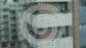 Raindrops on room window glass. Rainy weather in city. Dramatic cityscape.