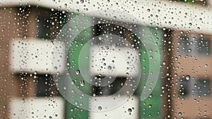 Raindrops on room window glass. Rainy weather in city. Dramatic cityscape.