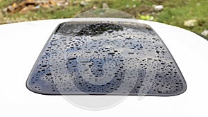 Raindrops on sunroof of a white car. Selective focus and closeup view
