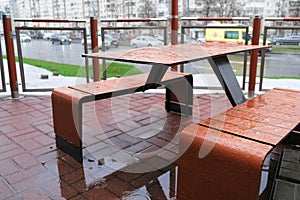 Raindrops on the tables and chairs of an empty street cafe