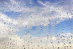 raindrops on wet glass against a cloudy sky