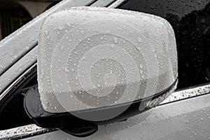 Raindrops on white car side rear-view mirror