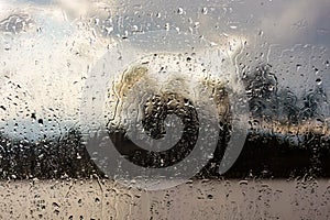 Raindrops on a window with a defocused lake landscape in the background