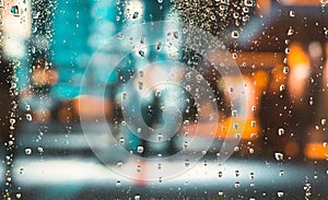 Rain drops on the window. Colorful street lights on the rain. Blurred abstract background.