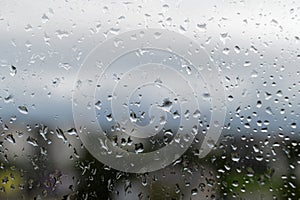 Raindrops on window glass, selective focus, rainy city background, wet glass, texture of raindrops