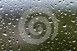 Raindrops on window glass, selective focus, rainy city background, wet glass, texture of raindrops