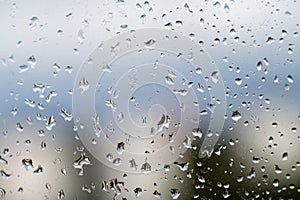 Raindrops on window glass, selective focus, rainy city background, wet glass, texture of raindrops