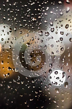 Raindrops on a window pane in the light of evening lights