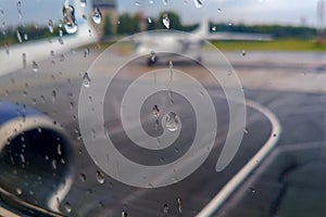 Raindrops on the window of the porthole, the plane is preparing to take off in bad weather