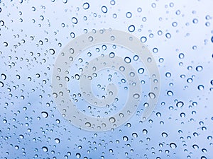 The raindrops on the windscreen or windshield or car glass. View from the inside of the car with a grey sky background. Adjust the