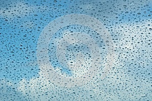 Raindrops on the windshield; in the background blue sky and white clouds, California