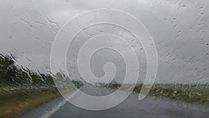 Raindrops on the windshield of the car rise up from the oncoming wind.