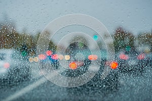 Raindrops on the windshield on a rainy day; blurred cars stopped