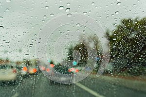 Raindrops on the windshield on a rainy day, traffic light on the background, California