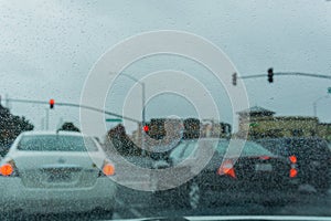 Raindrops on the windshield on a rainy day, traffic light on the background, California