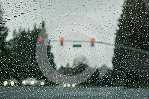 Raindrops on the windshield on a rainy day, traffic light background, California