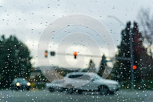 Raindrops on the windshield on a rainy day, traffic light background, California