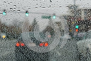 Raindrops on the windshield on a rainy day, traffic light background, California