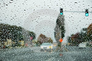 Raindrops on the windshield on a rainy day, traffic light background, California
