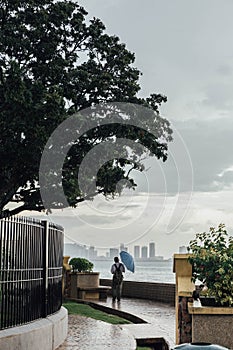 Raining in Park that near the Coast with a Man Holding Umbrella and Seeing Seascape and Cityscape of George Town, Penang, Malaysia