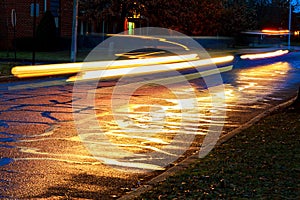 Rainstorm in the big city night, light from the shop windows reflected on the road which cars travel.