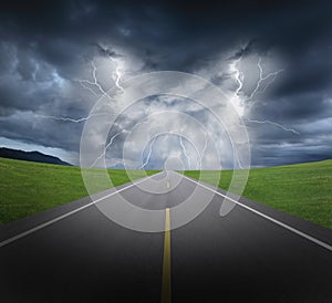 Rainstorm clouds and lightning with asphalt road and grass